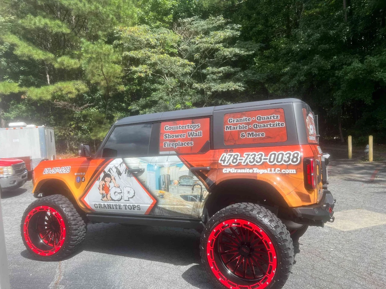 Orange and black lifted Jeep with bold commercial branding