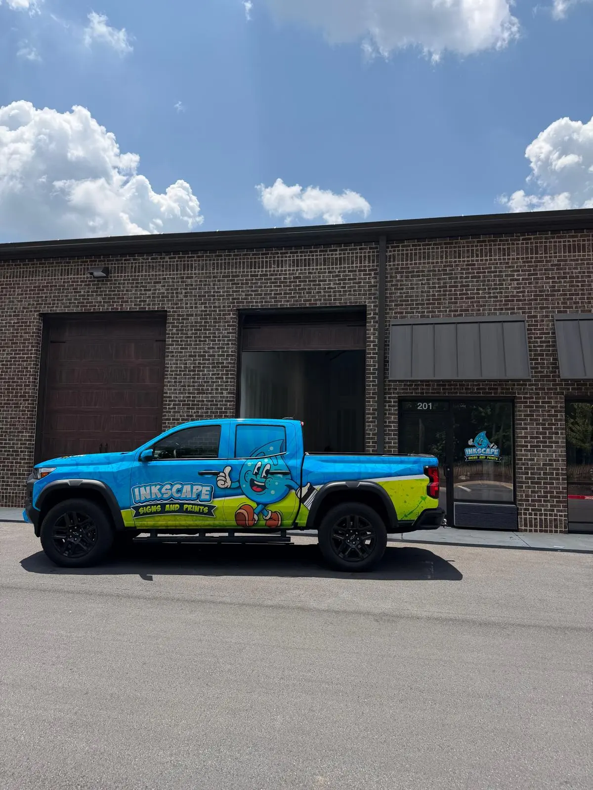 Inkscape Signs and Prints blue and green pickup truck outside the shop